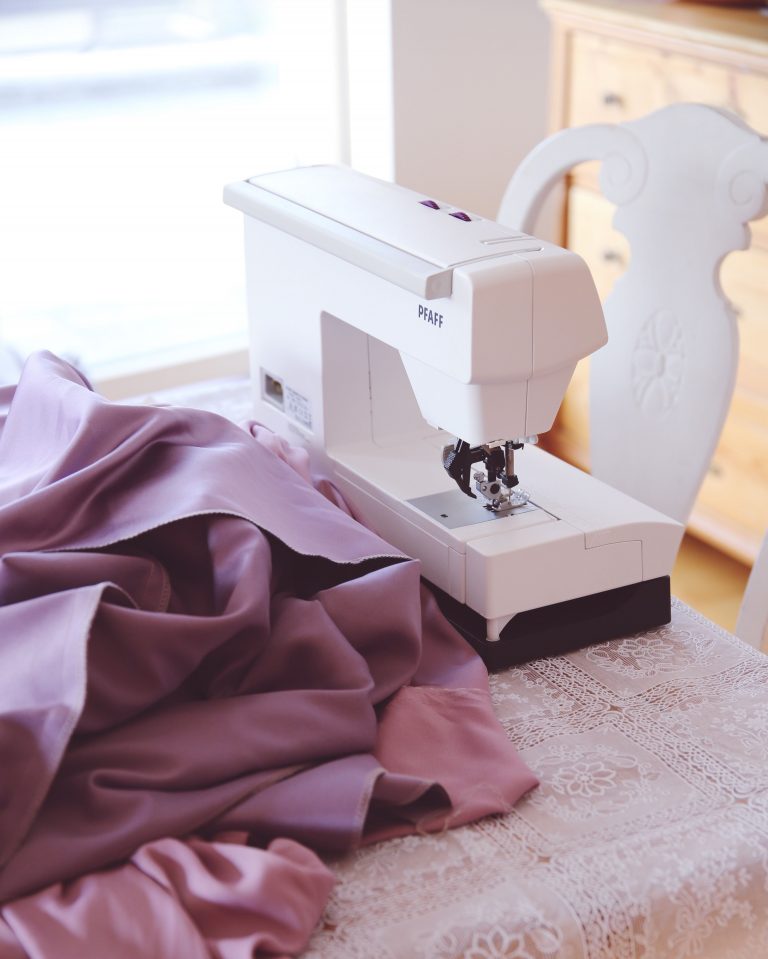 Nähmaschine mit lila Elfenstoffen darum herum